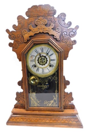 A late 19thC American mantel clock, in walnut gingerbread style case, the dial stamped Waterbury Clock Company USA, and with separate key wind alarm, 58cm high.