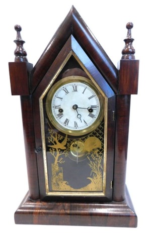 A late 19thC American mantel clock, in a rosewood case, the arched case with turned finials, above a later printed paper dial with gong enclosed by a gilt Aesthetic movement, verre eglomise door, 49cm high.