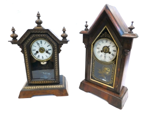 A late 19thC American mantel clock, in a figured mahogany arched case with turned finials, the paper dial enclosed by a black and gilt verre eglomise door, decorated with a single butterfly, 44cm high, and a similar German example by Junghans in a walnut,