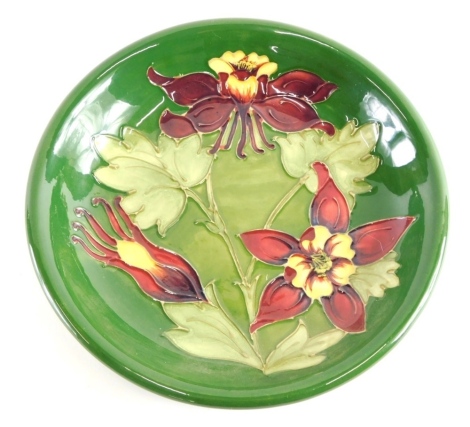 A Moorcroft pottery floral pattern plate, on green ground, impressed marks beneath, 22cm dimeter.