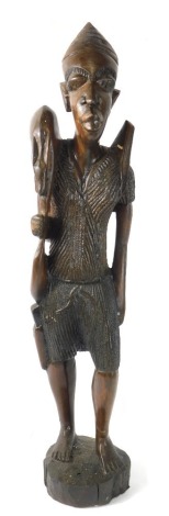 A carved African Tribal wooden figure, of a gentleman in standing pose, in textured clothing on carved base, 75cm high.