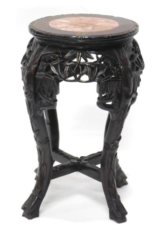 An early 20thC Chinese hardwood vase stand, with marble centre on heavily carved pierced cabriole legs joined by a cross stretcher, 50cm high, the top 29cm diameter.