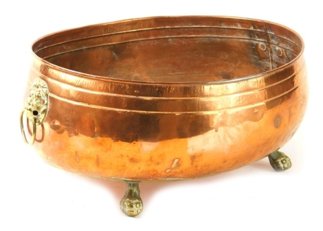 An early 20thC copper and brass planter, of oval form, with lion mask handles on hairy paw feet, 17cm high.