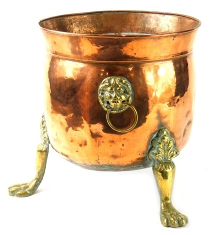 An early 20thC copper and brass planter, with bell shaped bowl, flanked by lions mask handles, on acanthus capped hairy paw feet 30cm high, the top 30cm diameter.