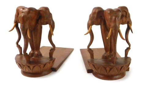 A pair of carved wooden tribal bookends, with triple elephant heads to each end, 20cm high. (2)