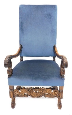 A late 19thC continental walnut open armchair, with a blue upholstered padded back and seat, the scroll arms carved with leaves and roundels on Braganza shaped feet, with an elaborate carved pierced leaf and scroll frieze and H stretcher.