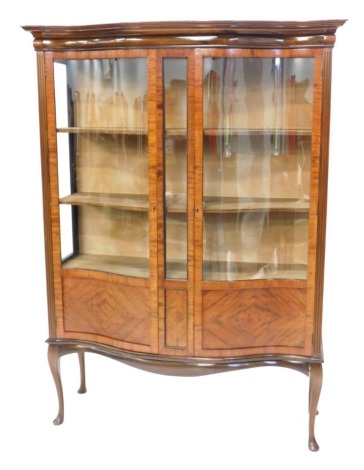 An Edwardian mahogany serpentine fronted display cabinet, with a moulded cornice over two glazed doors, with two glazed and panelled doors, flanked by glazed sides, on cabriole legs with pad feet, 180cm high, 132cm wide.