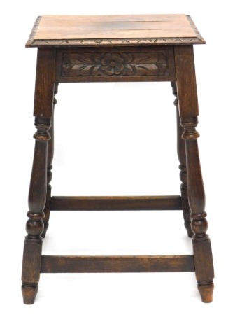 An oak occasional table, the square top with a carved moulded edge above a florally carved frieze on part turned supports with stretchers, 72cm high, 51cm wide.