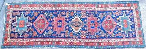 A Persian runner, with a design of medallions on a navy blue ground with three narrow borders, 268cm x 90cm.