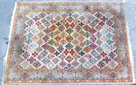 An Indian style rug, with an all over design of medallions, flowers, etc., on a beige ground with one wide and four narrow borders, 232cm x 107cm.