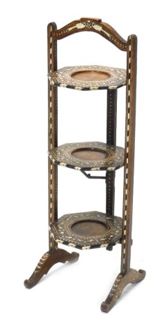 An late 19th/ early 20thC Indian hardwood and bone three tier folding cake stand, decorated with geometric devices, birds, leaves, etc., 77cm high.