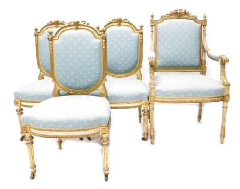 A late 19th/ early 20thC French gilt gesso and painted open armchair, the crest decorated with torches, flower heads, etc., with a padded back, armrests and seat, on fluted turned legs, and three associated side chairs, (4).