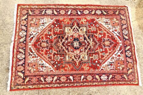 A Herez style small carpet, with a geometric design of medallions, lozenges, etc., on a red ground, with one wide and two narrow borders, 42cm x 172cm.