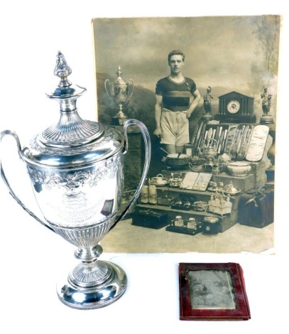 A Victorian silver trophy and cover, of twin handled semi fluted form, embossed with flowers and scrolling leaves, engraved to the front with an armorial shield, and engraved Essex Amateur Championship Cup, Two Miles Walking, Presented by Sir James Blythe