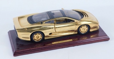 A Jaguar XJ 220 diecast model, in gold on a wooden plinth, in a fitted case. - 2