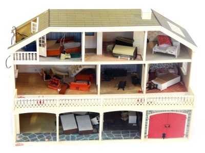 A Lundby doll's house, the house with a tiled roof, and glazed window panels with balcony and lower tier, with an open interior, and various plastic furniture, 64cm high, 92cm wide, 37cm deep.