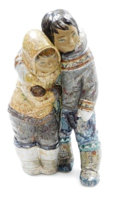 A Lladro porcelain figure group of an Inuit boy and girl, modelled standing in embrace, printed marks, 38cm high.