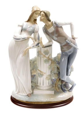 A Lladro porcelain figure group of Romeo and Juliet, modelled leaning against a central fluted column, printed marks, 42cm high, on an associated hardwood base.