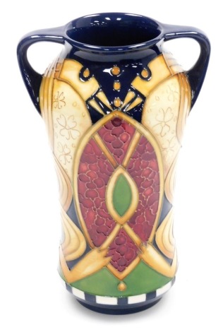 A Moorcroft pottery two handled vase decorated in The Anna Lily pattern, of cylindrical waisted form, 19cm high, boxed with outer slip case.