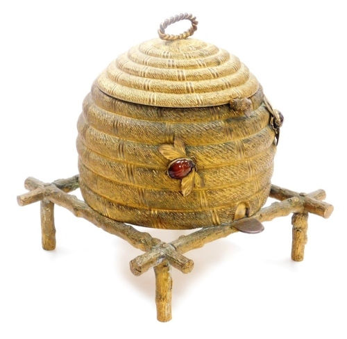 A 19thC gilt metal sewing box in the form of bee skep, with a hinged lid and twisted top handle, the body with two agate stone set applied honey bees and a honey bee catch, on a branch work stand, 24cm high, (AF).