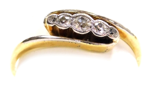 An Art Deco diamond three stone ring, in a crossover design set in yellow metal and white metal, approximately 0.2 carats, size E, 2.6g.