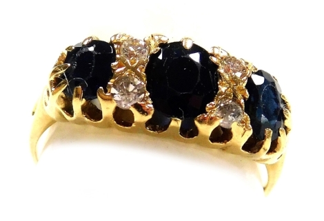 A sapphire three stone ring, set with pairs of diamonds at intervals, in yellow metal stamped 18ct, size J/K, 3.5g.