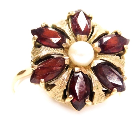 A late 20thC garnet and pearl set flower head ring, in a yellow metal basket setting, with engraved foliate decoration, size W, 5.2g.