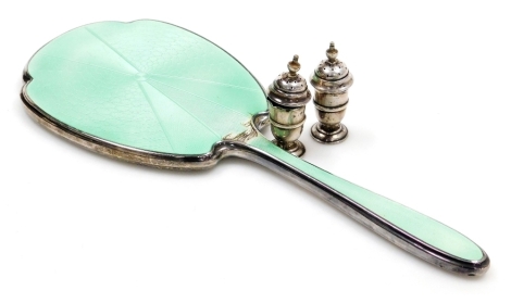 A pair of Edward VII silver miniature pepper pots, of baluster form with an urn shaped finial and raised central band, Birmingham 1907, 5.5cm high, and a green enamel and silver mounted hand mirror, Birmingham 1938. (3, AF)
