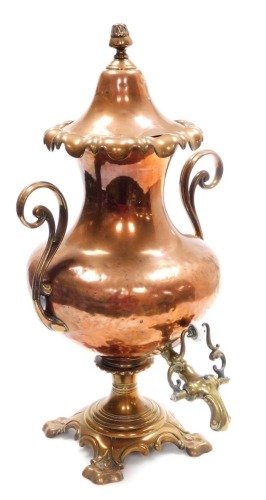 A 19thC copper and brass tea urn, with a conical lid and shaped flared rim, tapering neck and bulbous body, flanked by two pierced scroll handles, on a shaped quatrefoil base, with a brass spout, 56cm high.