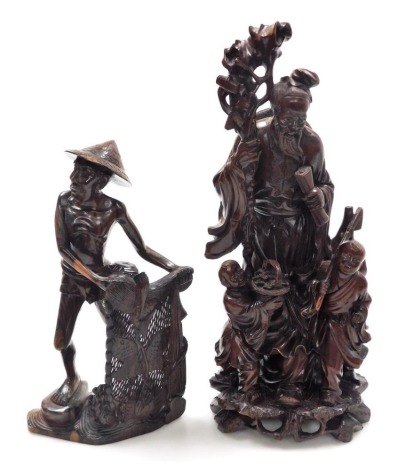 A 20thC hardwood carving of Shou-Lau, carved with a staff and two attending children, 41cm high, and a further Oriental hardwood carving of a fisherman with net, 31cm high.