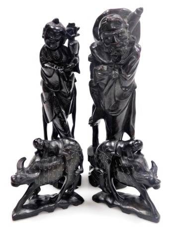 Two Chinese hardwood figures of deities, with silver wirework inlay, 29cm high and 28cm high, and two figures modelled as boys riding on buffaloes, 12cm wide.