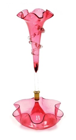 A Victorian cranberry glass single epergne, with a central trumpet horn, with flared rim and applied moulded glass decoration, on a shaped and moulded circular base, 35.5cm high.