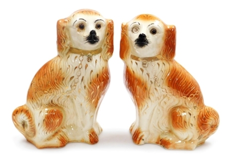 A pair of early 20thC Staffordshire style Spaniels, in a mottled orange glaze, gilt heightened, with glass eyes (1 missing), 34cm high.