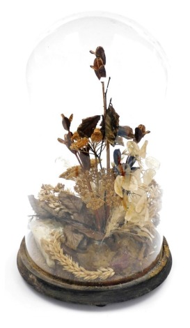 A Victorian glass dome, containing an arrangement of dried flowers, pine cone, etc., mounted on a hard stone base, the dome 37cm high.