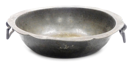 A 19thC pewter two handled dish, of circular form, with a shaped edge and drop handles, indistinct impressed marks to underside, 34cm diameter.