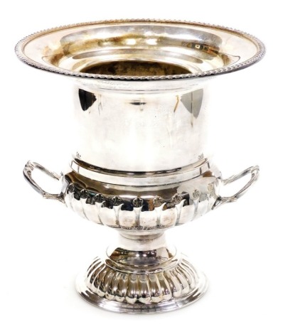 An early 20thC silver plated campana wine cooler, with a flared gadrooned rim, cylindrical part fluted body, with two handles, and a part gadrooned circular stepped base, with removable liner, 25cm high.