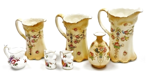 A set of three graduated Crown Devon Fielding blush pottery jugs, each decorated with flowers, pheasants, etc., gilt heightened, the largest 21cm high, a similar bud vase, 13.5cm high (AF), together with three Royal Crown Derby Derby Posies miniature jugs