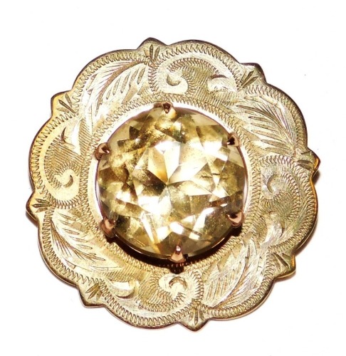 A 9ct gold and cairngorm circular brooch, claw set in a foliate engraved surround, approximately 9 carat, 5.0g.