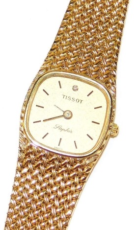 A Tissot Saphir 9ct gold lady's wristwatch, square champagne dial with gold batons, set at twelve with a diamond, on a mesh bracelet strap, 27.3g all in.