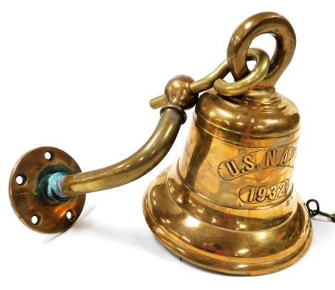 A US Navy 1932 ship's brass bell, with wall support, the bell 24cm high.