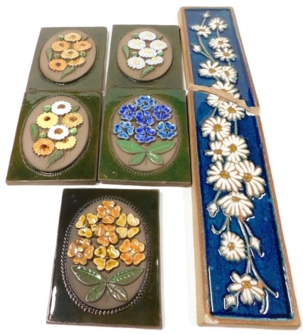 A set of five Swedish pottery wall tiles, each decorated in relief of different flowers, each plaque 22.5cm x 17cm, and a Danish Bornholm floral decorated plaque, of rectangular form, decorated with daisies, against a blue glazed ground (AF), approximatel