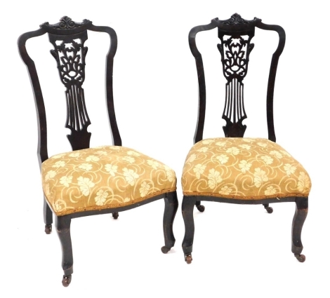 A pair of Victorian mahogany nursing chairs, each with a shaped pierced back, overstuffed seats, raised on cabriole legs on castors, 87cm high.