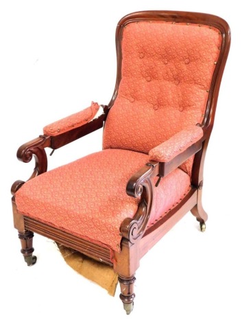 A Victorian mahogany spoon back reclining library chair, with an overstuffed button back, seat, and arms, with scroll carved arm supports, raised on fluted legs on castors.