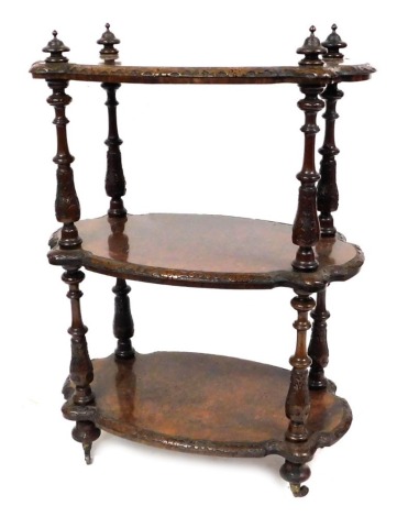 A Victorian walnut and burr walnut three tier whatnot, each shaped tier with scroll carved edging, connected by four turned and carved supports, raised on carved bun feet on castors, 106cm high, 74cm wide, 46cm deep.