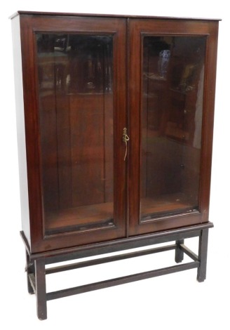 A Victorian mahogany display cabinet, with two rectangular glazed doors, enclosing an arrangement of shelves, on an associated base, 156cm high, 110cm wide, 32cm deep.