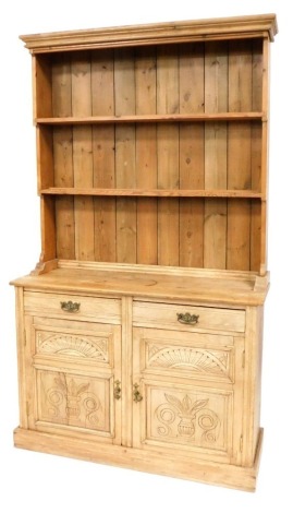 A Victorian pine dresser, the top with moulded cornice above a plate rack with two shelves, the base with two drawers above two carved and panelled drawers, on a plinth base, 206cm high, 132cm wide, 40cm deep.