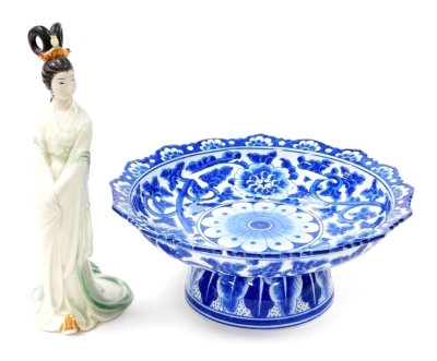 A Chinese blue and white table centre stand, painted with chrysanthemums and trailing foliage, 12.5cm high, 31.5cm diameter, and a Chinese pottery standing figure of a young woman in flowing gown, 30.5cm high. (2)