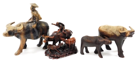 An Oriental simulated hardwood figure group of a boy riding a water buffalo, 18cm high, 19cm long, and three other water buffalo figures. (4)