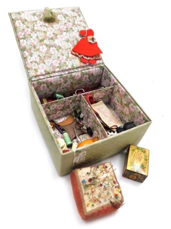 A sewing box, containing assorted accoutrements, including a Killarney pin cushion modelled as the bust of a child, needle cases, box, pin cases, darning needles, etc.