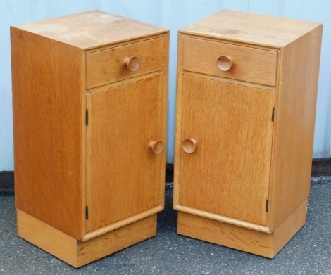 A pair of Meredew light oak bedside cupboards, each with a single drawer over a cupboard door, raised on a plinth base, 64.5cm high, 31.5cm wide, 30.5cm deep.